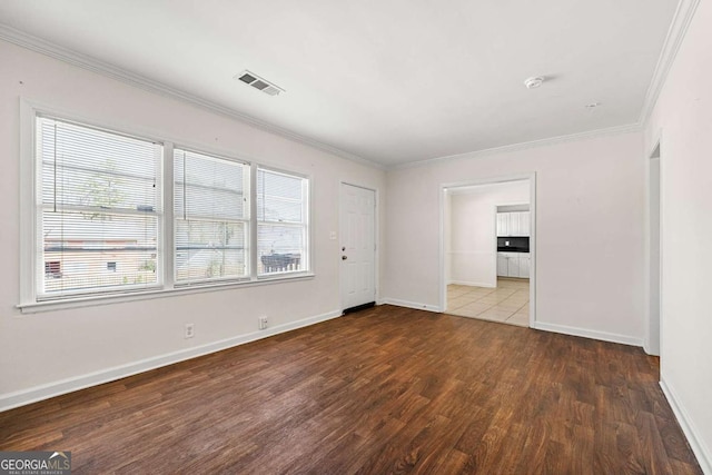 unfurnished room with dark wood-style floors, ornamental molding, visible vents, and baseboards