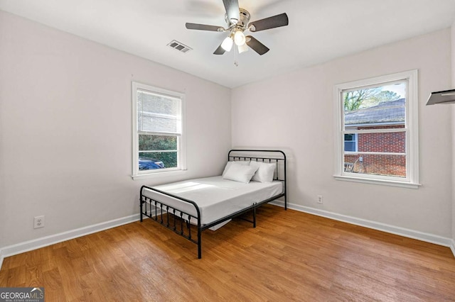 bedroom featuring light wood-style flooring, visible vents, baseboards, and ceiling fan