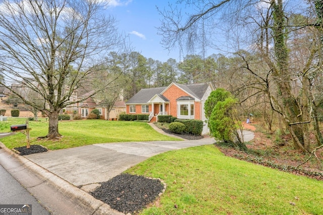 view of front of property featuring a front yard, brick siding, and driveway