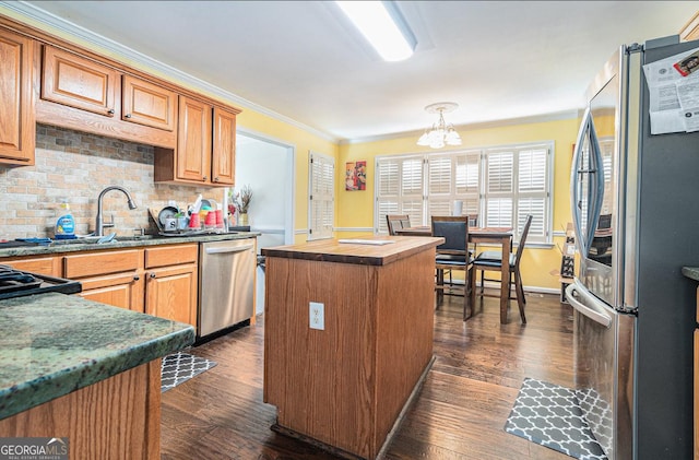 kitchen featuring a center island, dark wood finished floors, backsplash, appliances with stainless steel finishes, and a sink