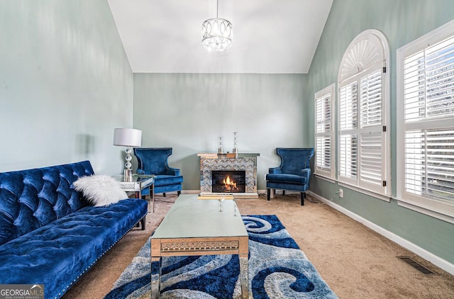 carpeted living area featuring visible vents, vaulted ceiling, a chandelier, a lit fireplace, and baseboards