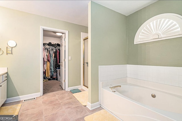 full bathroom featuring a stall shower, a garden tub, vanity, and a walk in closet