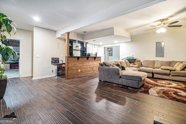 living area featuring ceiling fan, bar, wood finish floors, baseboards, and electric panel