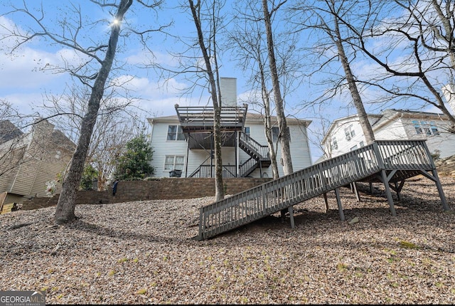 rear view of house featuring stairs, a chimney, and a deck