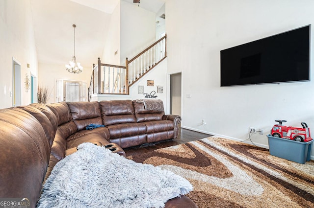 living room with a high ceiling, dark wood-style flooring, baseboards, stairway, and an inviting chandelier