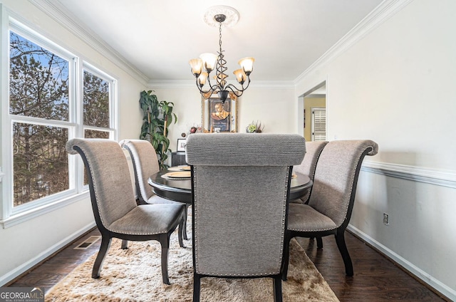 dining area featuring baseboards, visible vents, wood finished floors, crown molding, and a chandelier