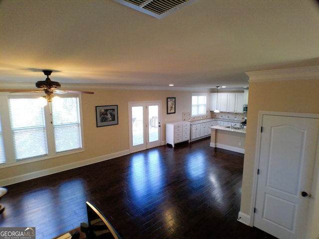 unfurnished living room featuring ornamental molding, dark wood finished floors, visible vents, and baseboards