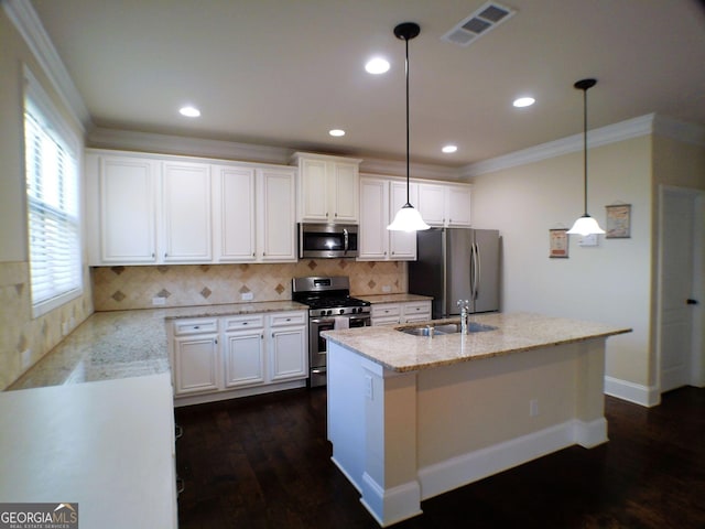 kitchen featuring visible vents, an island with sink, ornamental molding, stainless steel appliances, and a sink