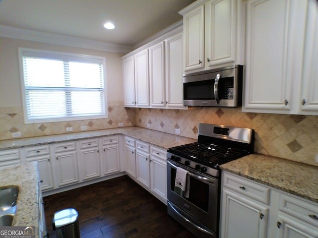 kitchen with dark wood-style flooring, tasteful backsplash, appliances with stainless steel finishes, ornamental molding, and white cabinetry