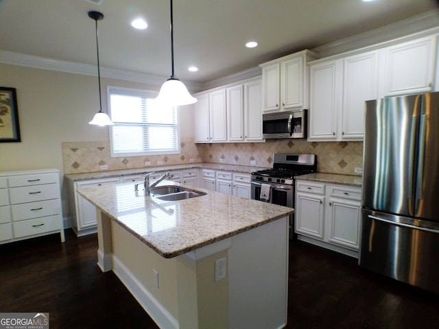 kitchen with a center island with sink, white cabinets, ornamental molding, stainless steel appliances, and a sink