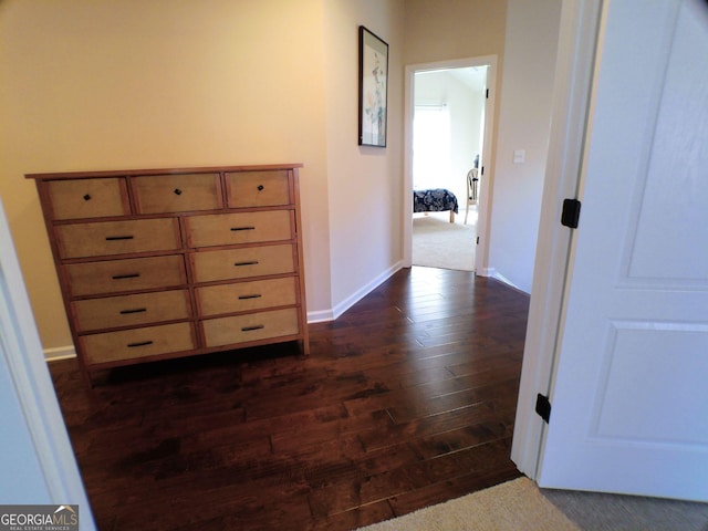 hallway featuring dark wood-style flooring and baseboards