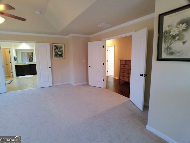 interior space featuring lofted ceiling, connected bathroom, baseboards, ornamental molding, and carpet