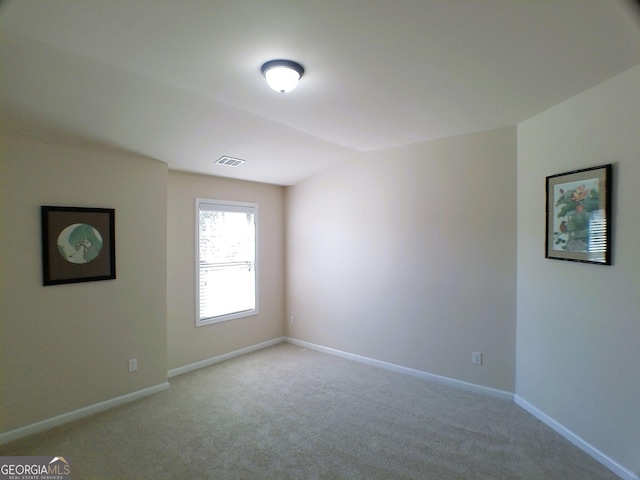 carpeted spare room featuring visible vents and baseboards