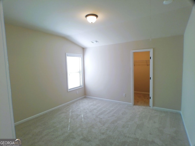 carpeted spare room with baseboards, visible vents, vaulted ceiling, and attic access