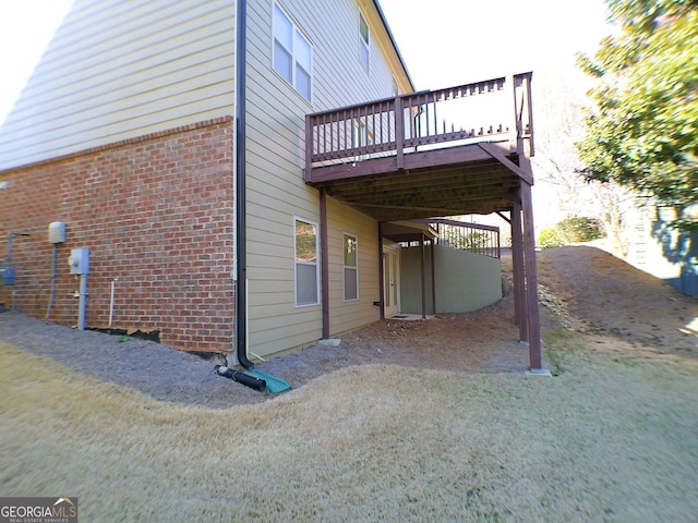 view of home's exterior with a yard, brick siding, and a wooden deck