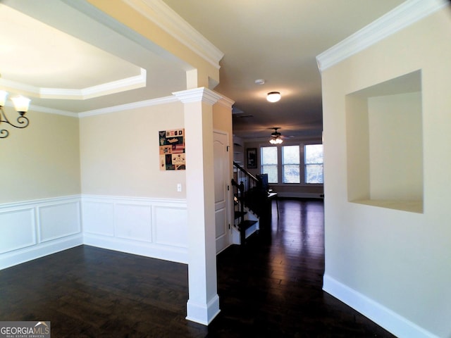 hallway featuring wainscoting, stairway, dark wood-type flooring, crown molding, and a notable chandelier