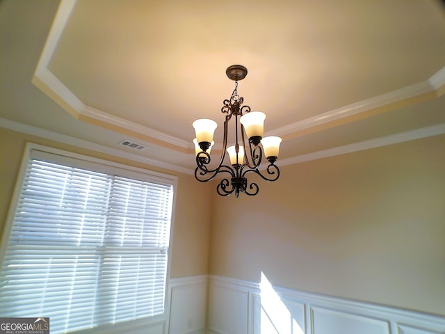 room details with a raised ceiling, visible vents, wainscoting, and an inviting chandelier