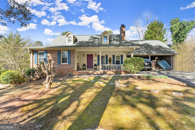 view of front of home with a porch, brick siding, driveway, a front lawn, and a chimney