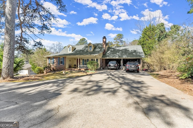 view of front of home with driveway, a chimney, and a carport