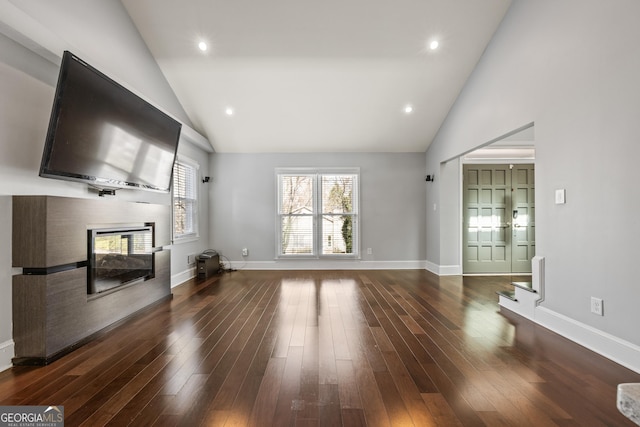 unfurnished living room featuring high vaulted ceiling, wood finished floors, a multi sided fireplace, and baseboards