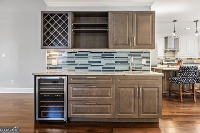 bar featuring wine cooler, dark wood finished floors, a dry bar, and wall chimney exhaust hood