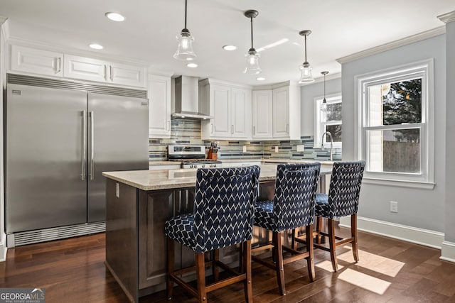 kitchen featuring stainless steel appliances, wall chimney range hood, backsplash, and white cabinets