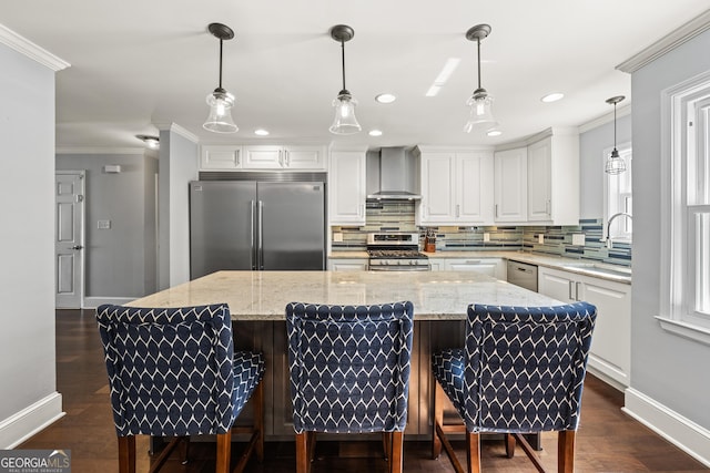 kitchen featuring backsplash, appliances with stainless steel finishes, ornamental molding, white cabinetry, and wall chimney exhaust hood