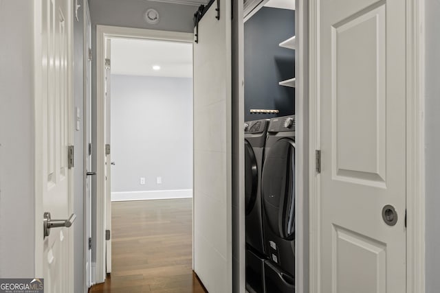 interior space featuring a barn door, dark wood-style flooring, washing machine and clothes dryer, and baseboards