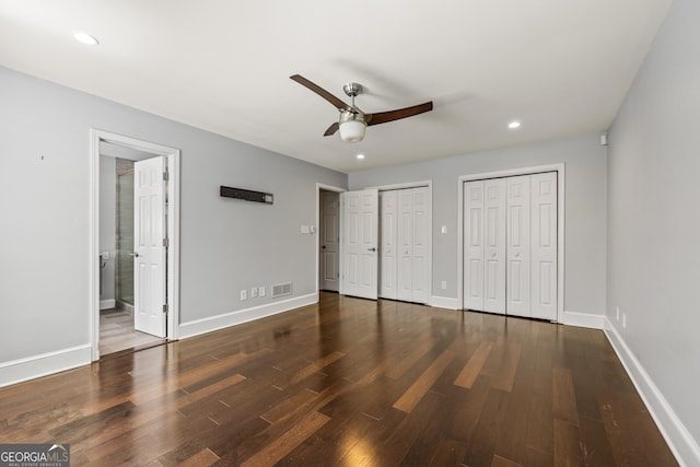 unfurnished bedroom with multiple closets, visible vents, baseboards, and wood finished floors