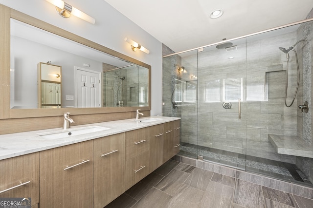 full bath featuring a stall shower, a sink, and double vanity