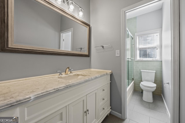 bathroom featuring shower / bath combination with glass door, tile walls, toilet, vanity, and tile patterned floors