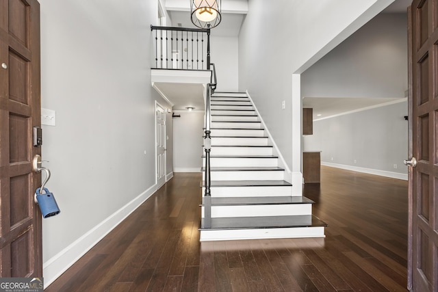 foyer featuring a high ceiling, stairway, wood finished floors, and baseboards