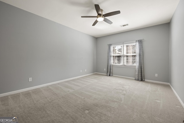 carpeted empty room with baseboards, visible vents, and a ceiling fan