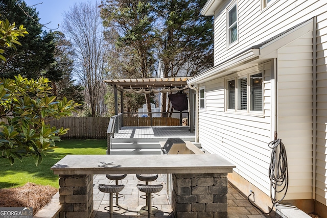 view of patio / terrace featuring fence, outdoor dry bar, and a wooden deck