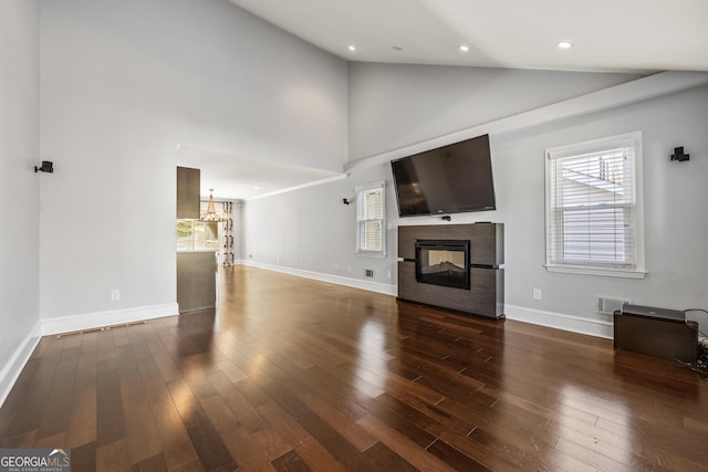 unfurnished living room with dark wood-type flooring, a multi sided fireplace, visible vents, and baseboards