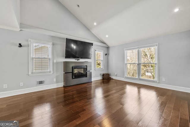 unfurnished living room with high vaulted ceiling, dark wood-style flooring, a multi sided fireplace, visible vents, and baseboards