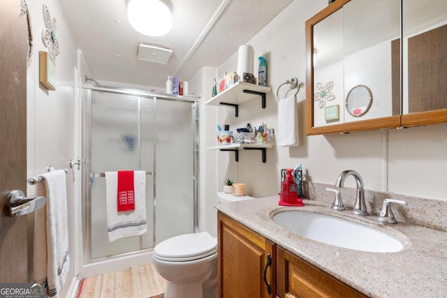 full bathroom featuring toilet, a stall shower, and vanity