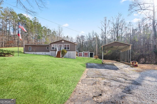 view of yard featuring aphalt driveway, an outdoor structure, a carport, and a storage shed