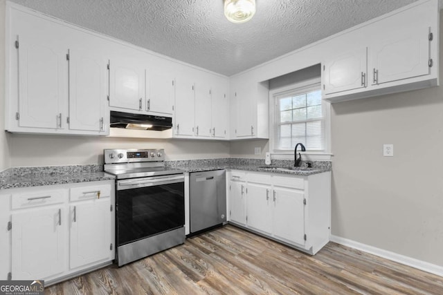 kitchen with stainless steel appliances, a sink, white cabinets, and under cabinet range hood