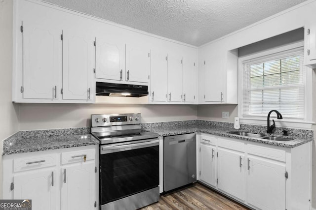 kitchen featuring dark wood finished floors, stainless steel appliances, under cabinet range hood, white cabinetry, and a sink