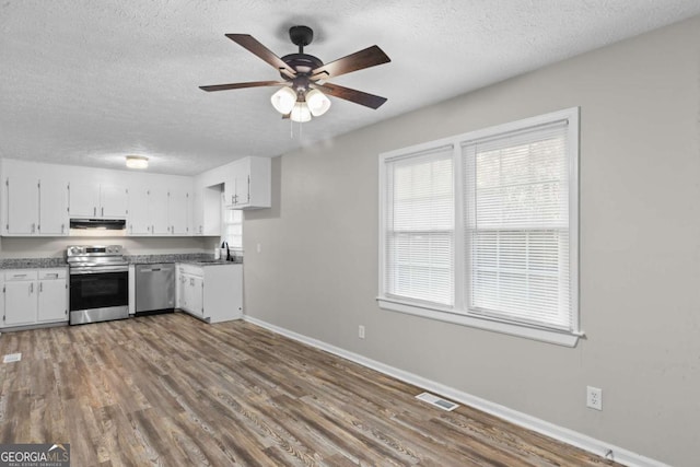 kitchen with visible vents, appliances with stainless steel finishes, white cabinetry, a sink, and under cabinet range hood