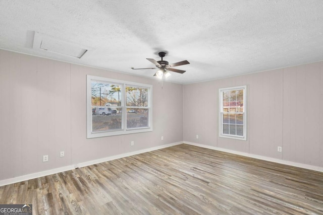 empty room featuring a textured ceiling, wood finished floors, and baseboards