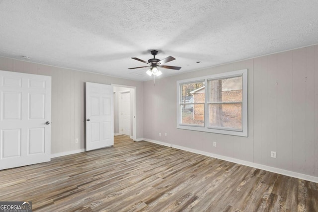 unfurnished room featuring a textured ceiling, wood finished floors, and baseboards