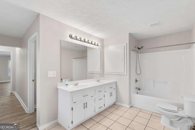 bathroom featuring double vanity, shower / bath combination, a sink, a textured ceiling, and tile patterned flooring