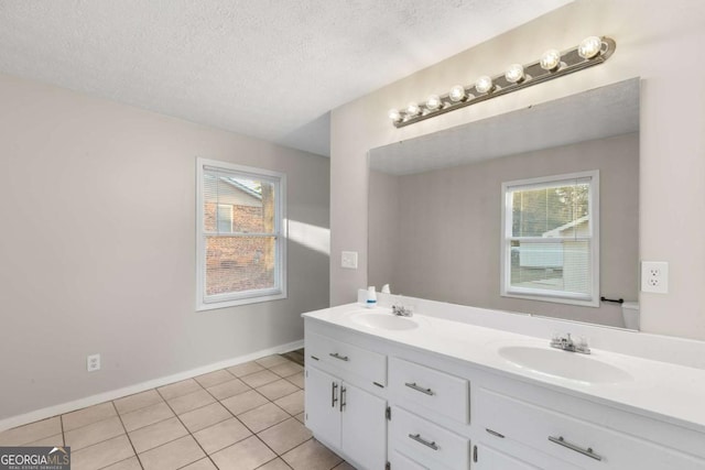 bathroom with a textured ceiling, double vanity, a sink, and tile patterned floors