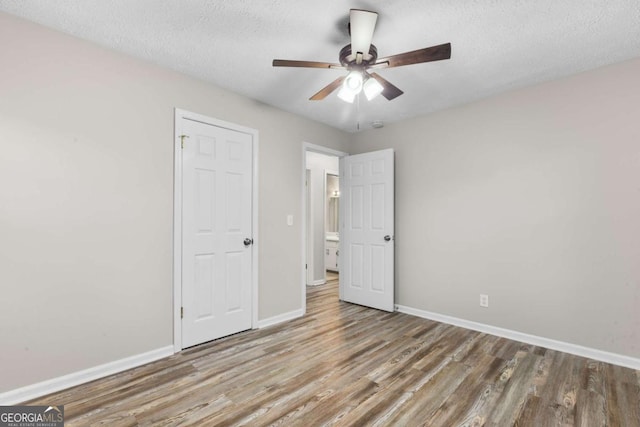 unfurnished bedroom featuring a textured ceiling, wood finished floors, and baseboards