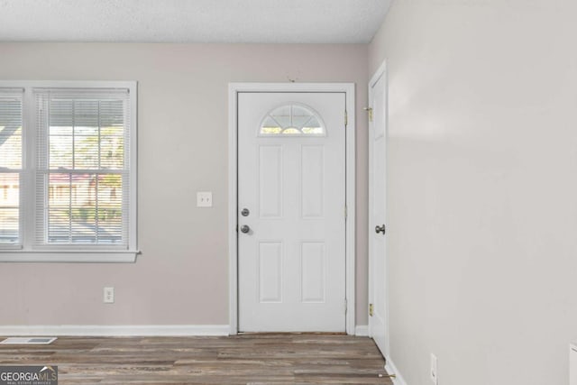 entrance foyer with a textured ceiling, wood finished floors, visible vents, and baseboards