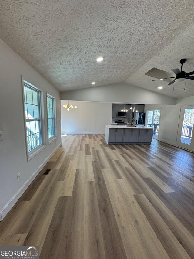 unfurnished living room featuring visible vents, vaulted ceiling, light wood-style flooring, and baseboards