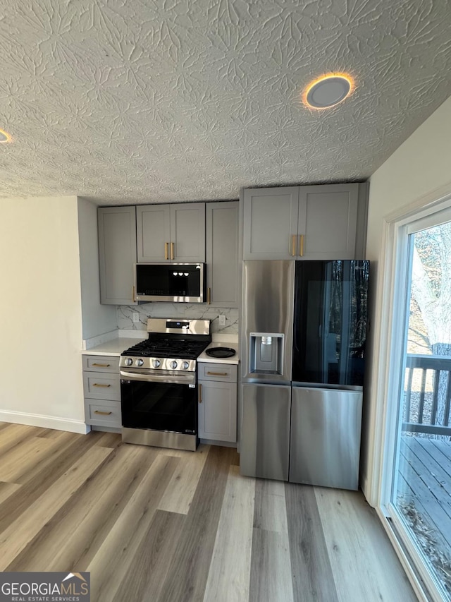 kitchen with light countertops, appliances with stainless steel finishes, light wood-style floors, and gray cabinetry