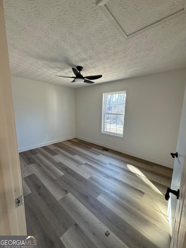 empty room featuring a ceiling fan, a textured ceiling, baseboards, and wood finished floors